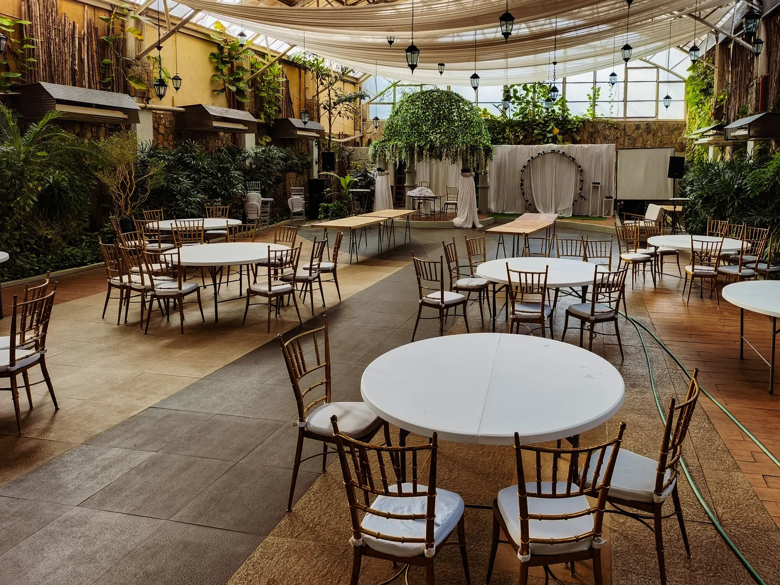 Salón para casamientos vacío con mesas redondas, sillas y vegetación