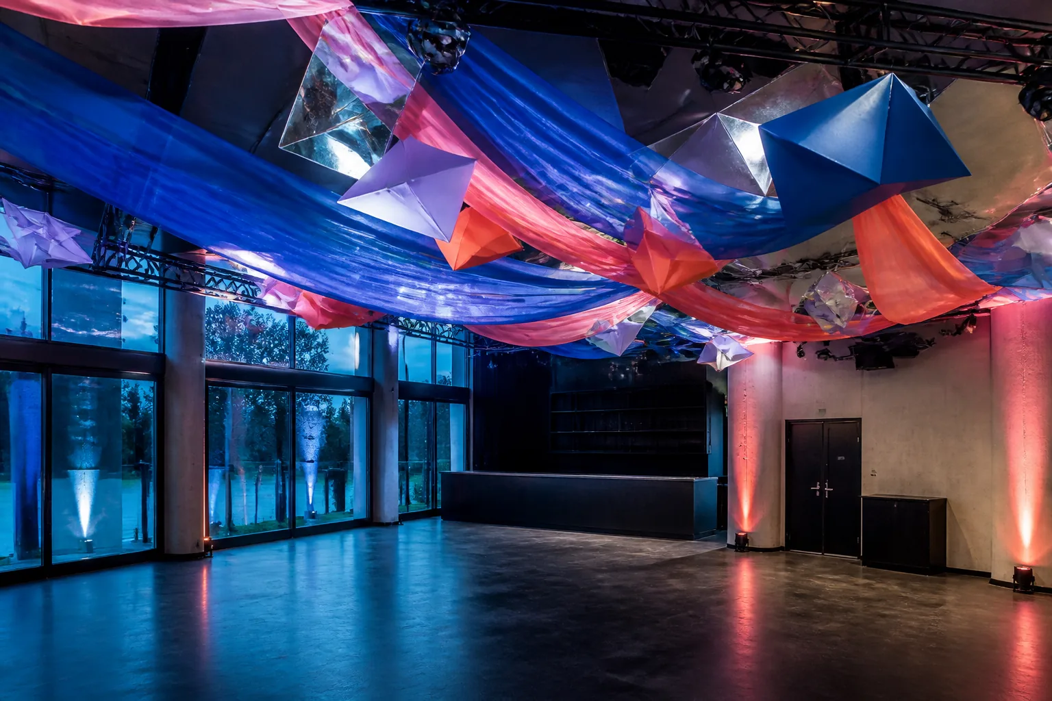 Salón vacío con instalación aérea gráfica azul y coral sobre la pista