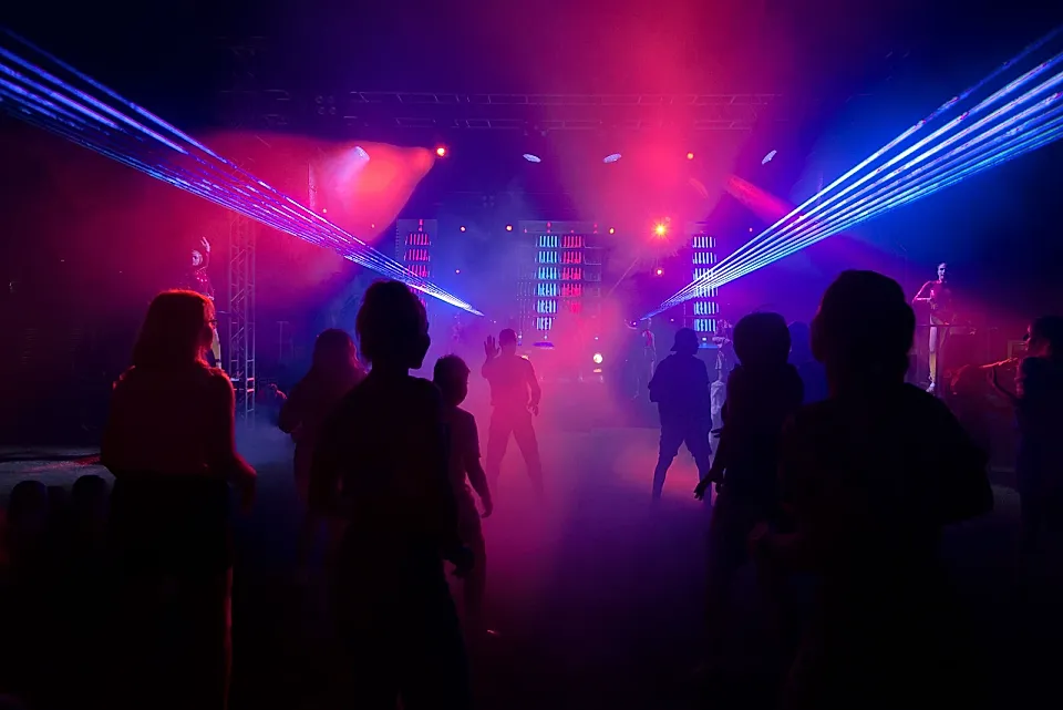Pista de baile con siluetas bajo luces violetas y azules
