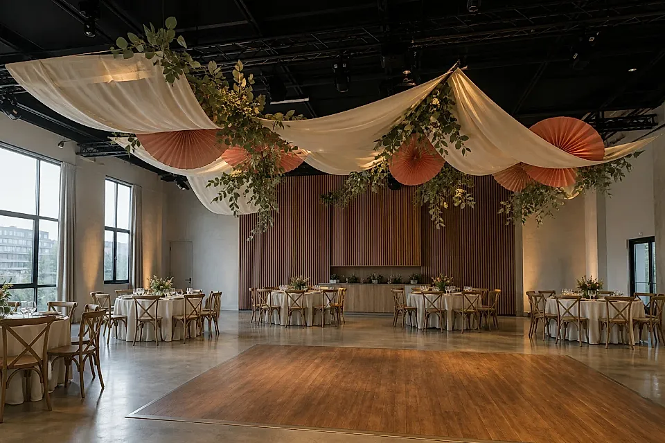Salón de casamiento con telas marfil, follaje y abanicos coral suspendidos sobre la pista