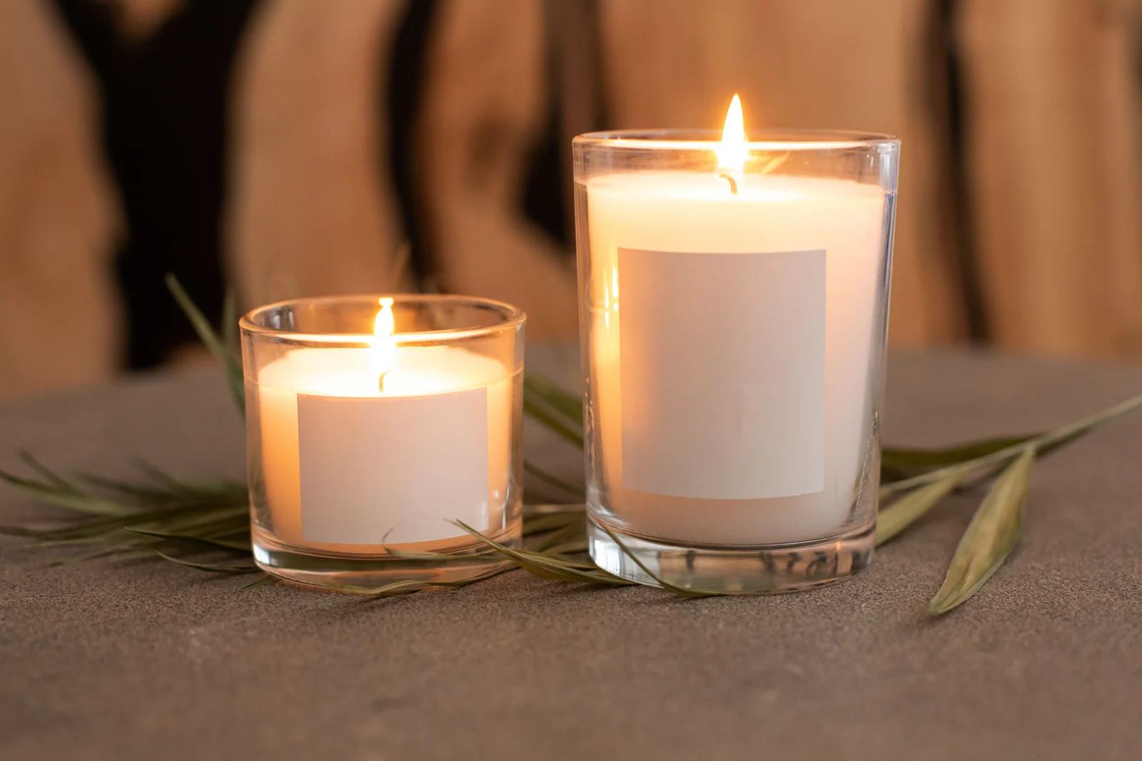 Dos velas aromáticas encendidas en frascos de vidrio con etiquetas en blanco