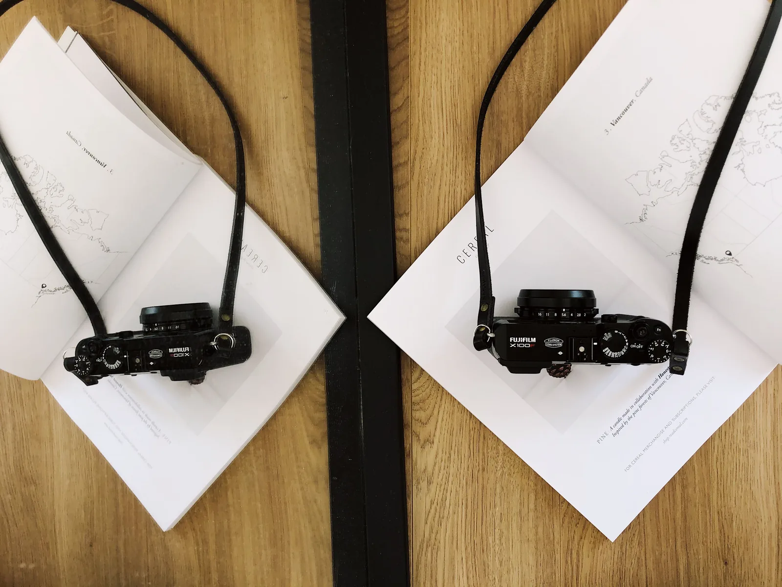 Dos cámaras fotográficas apoyadas sobre una mesa con libros abiertos