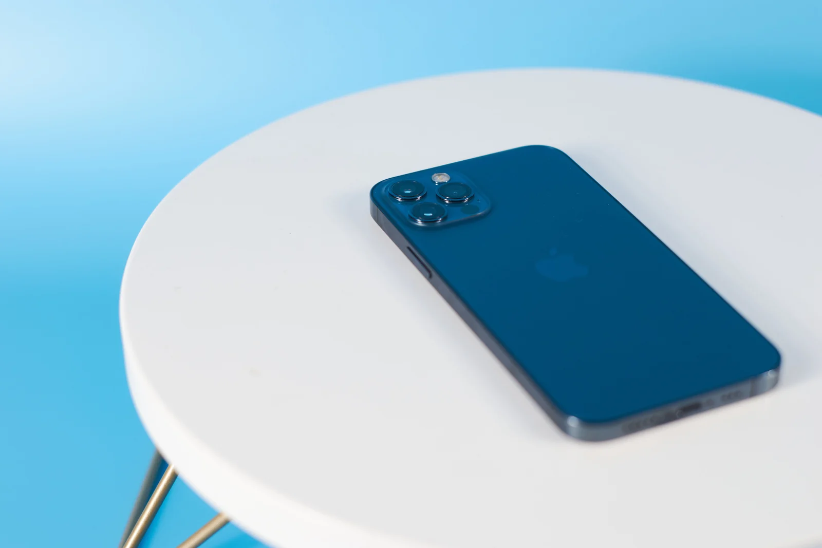 Teléfono azul con la pantalla hacia abajo sobre una mesa blanca.