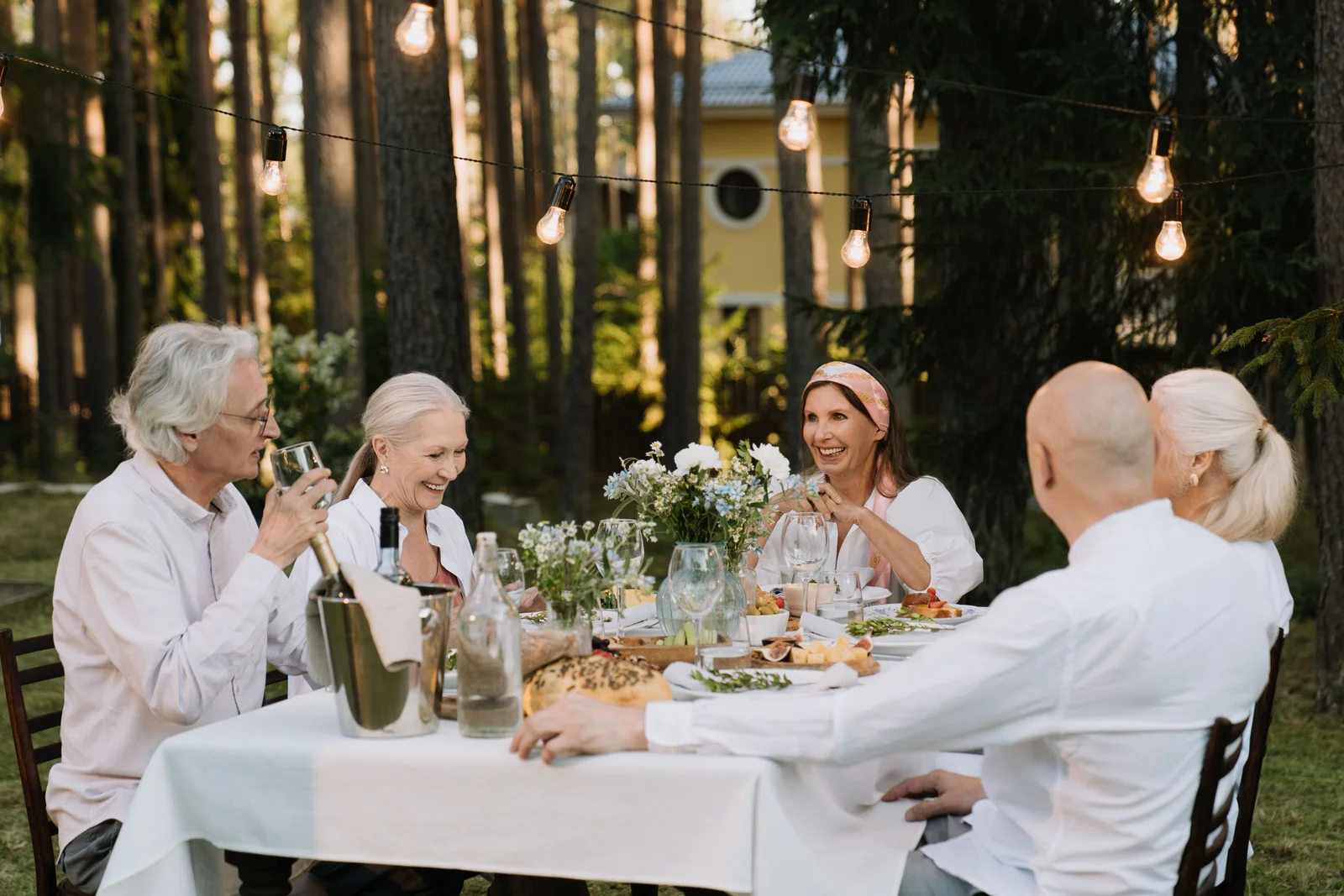 Personas mayores conversan y se ríen alrededor de una mesa al aire libre