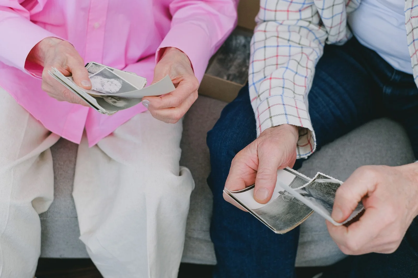 Dos personas mayores revisan fotografías familiares antiguas.