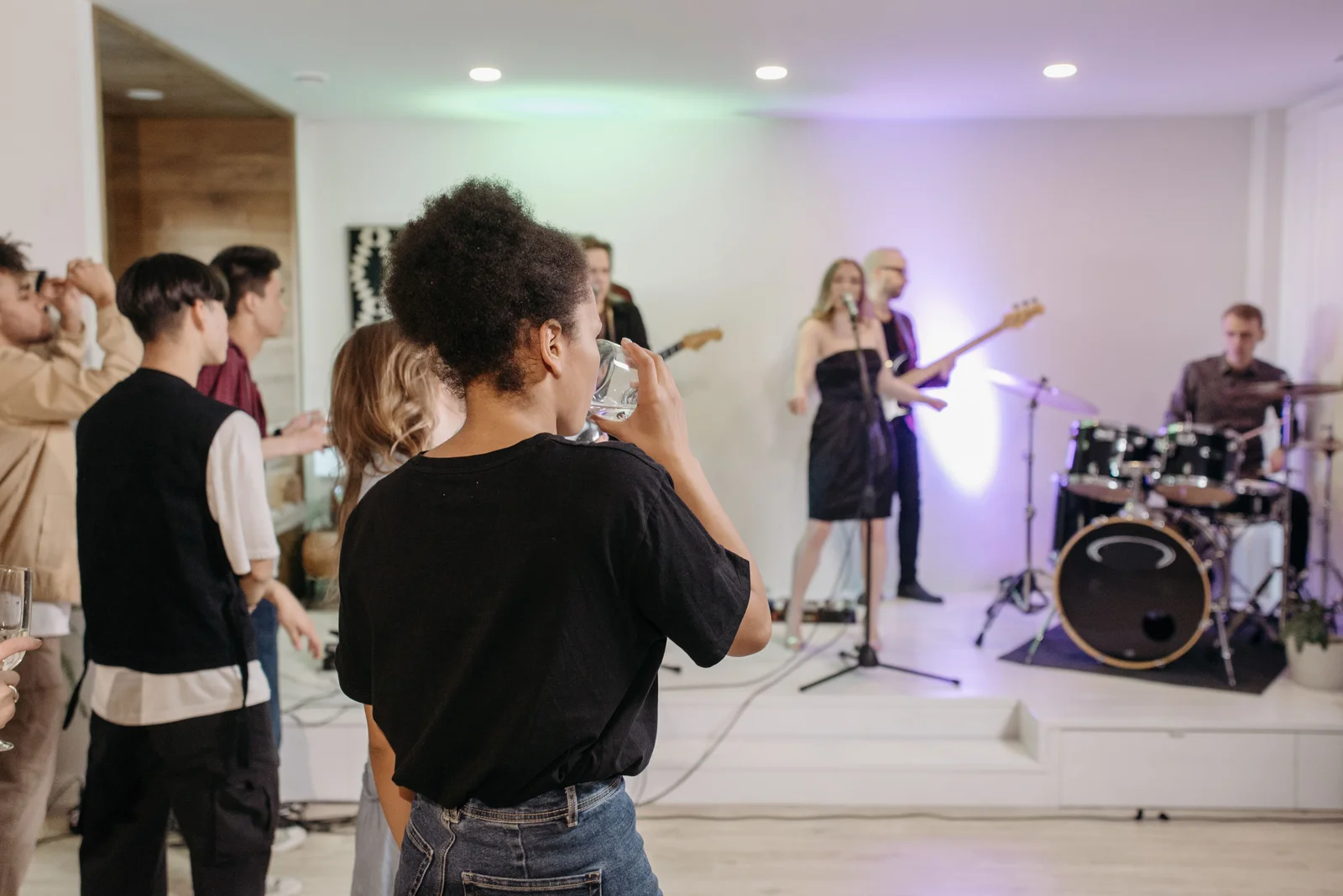 Jóvenes observan una banda con cantante y batería en una reunión.