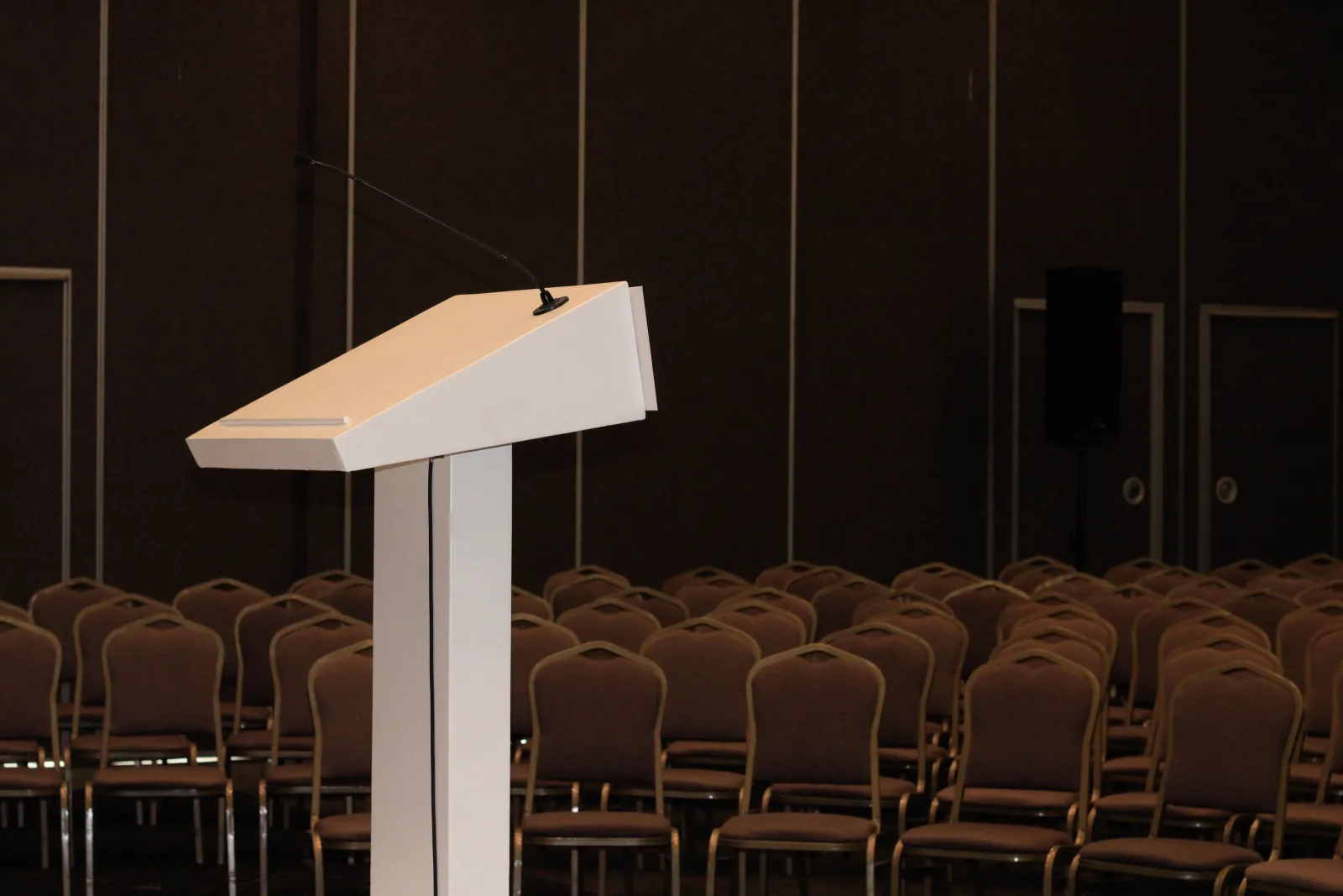Sala de conferencias vacía preparada con sillas, escenario y micrófono