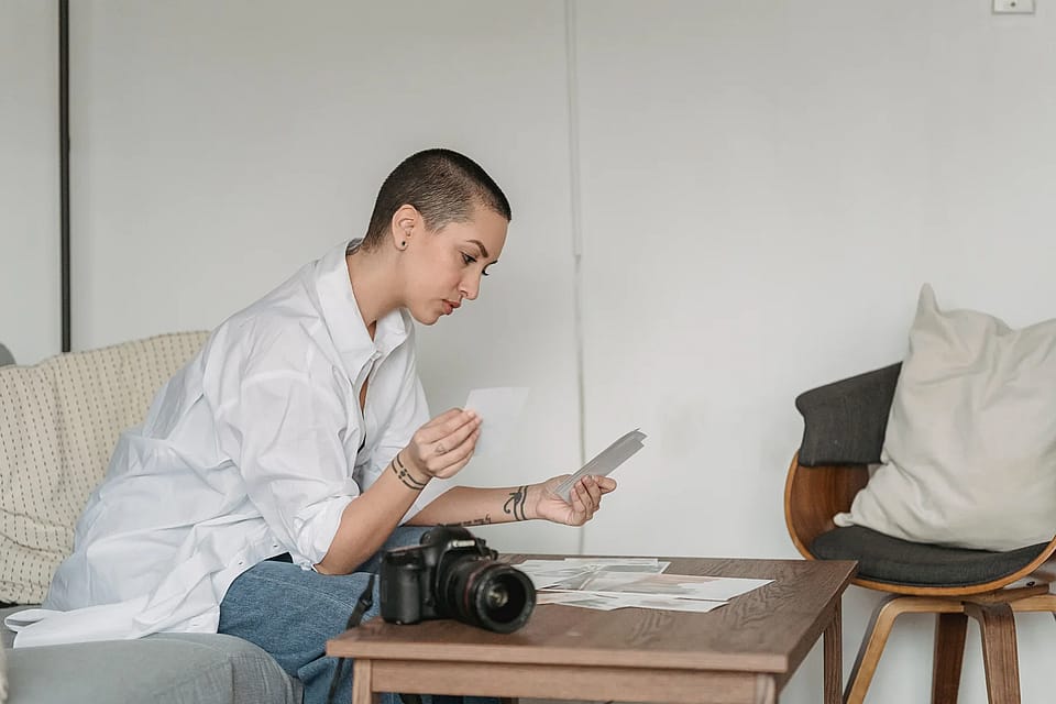 Fotógrafa revisando fotografías impresas junto a una cámara