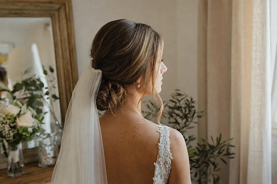 Novia de perfil con recogido boho suave y velo corto en luz natural