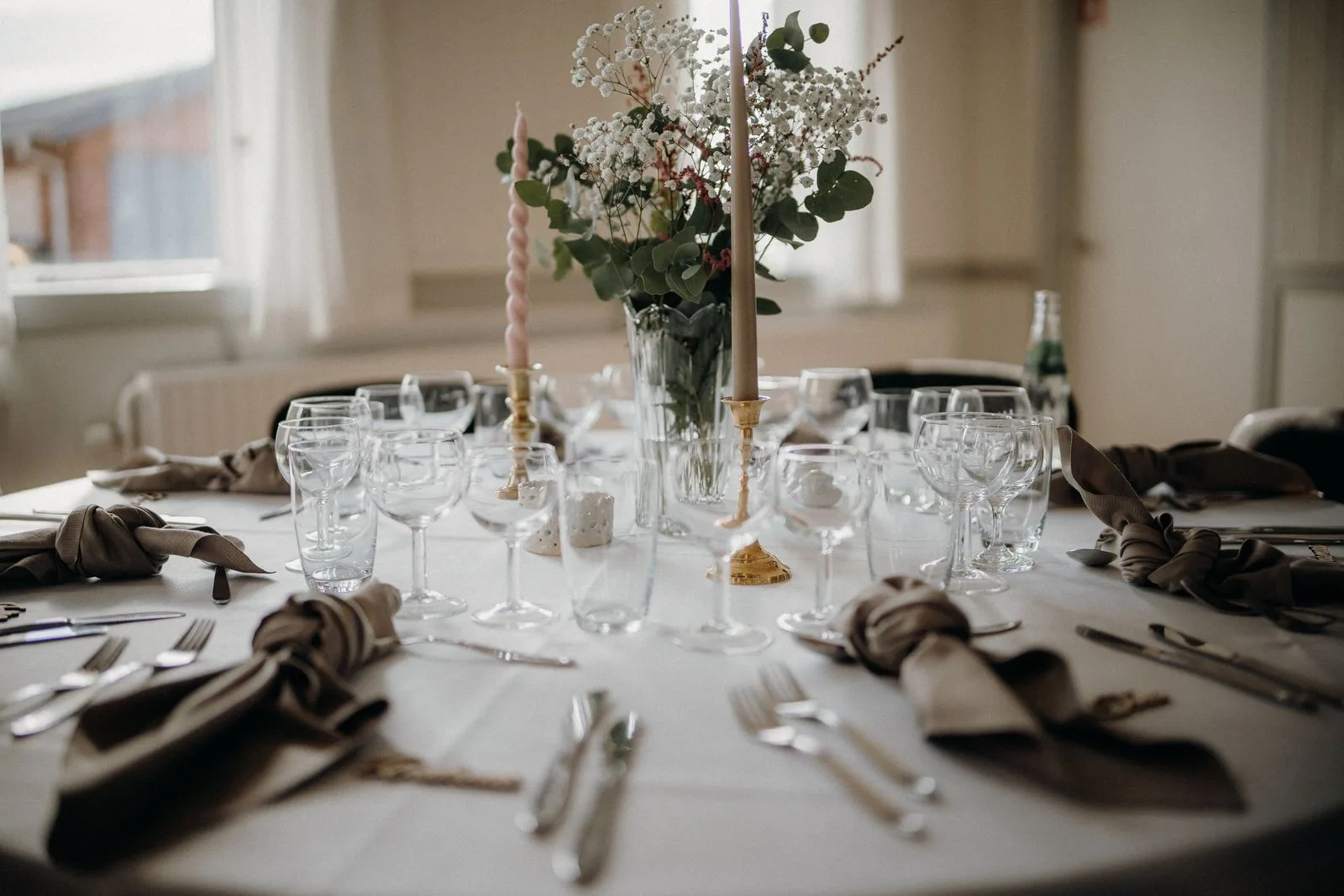 Mesa de casamiento con velas, flores blancas, copas y servilletas oscuras