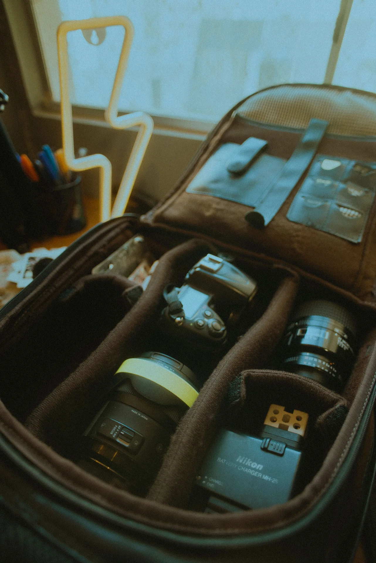 Bolso de fotografía abierto con una cámara, un objetivo y accesorios en compartimentos acolchados