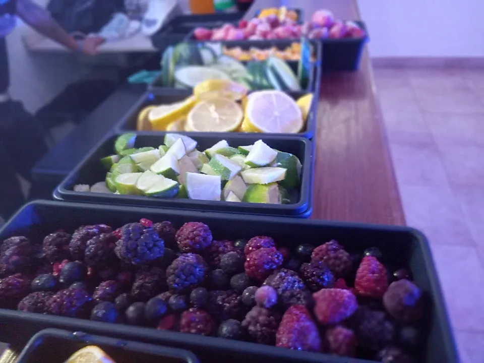 Bandejas con frutos rojos, cítricos y otros ingredientes preparados para una barra móvil